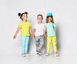 © FAB.1 - children on a light background: full body shot of three children in bright clothes, two girls and one boy. Triplets, brother and sisters.