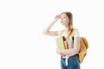 Wall Mural - curious schoolgirl with backpack holding books and looking away isolated on white