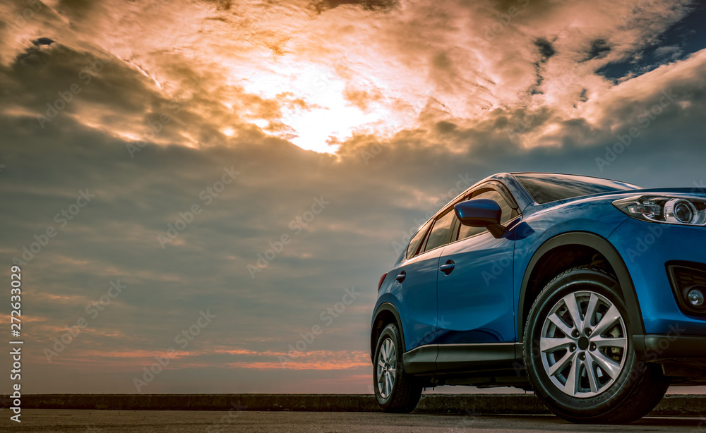 Blue compact SUV car with sport and modern design parked on concrete road by the sea at sunset in the evening. Hybrid and electric car technology concept. Car parking space. Automotive industry.