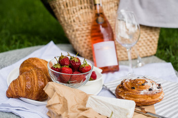 Wall Mural - Beautiful summer picnic with strawberries, cheese and rose wine on the lawn in the city park