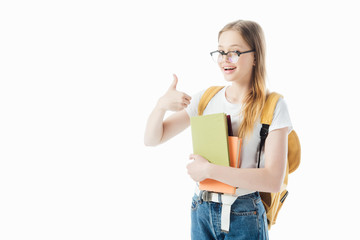 Wall Mural - smiling schoolgirl with backpack holding books and showing thumb up isolated on white