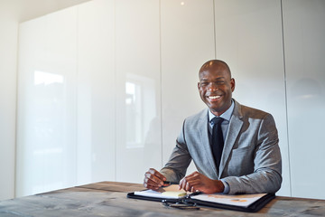 Wall Mural - Smiling African American businessman sitting with paperwork in a