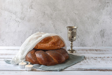 Shabbat Shalom - challah bread, shabbat wine and candles on light grey background