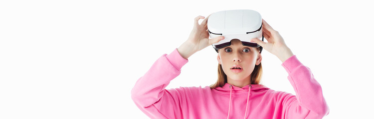 Wall Mural - panoramic shot of shocked teenage girl in pink hoodie wearing vr headset isolated on white