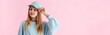 panoramic shot of pretty smiling teenage girl in cap isolated on pink