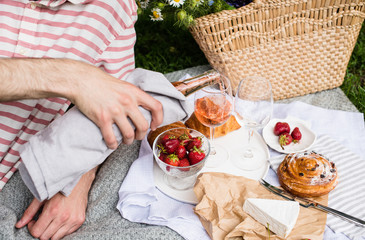 Man's hand pouring rose wine into glasses, summer picnic