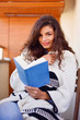 © nikodash - Young woman reads a book at balcony