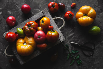 Fresh tomatoes in an old box. On wooden background.