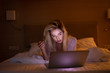 © lashkhidzetim - Bedroom evening - woman with laptop lying down in bed.