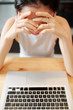 © DragonImages - Young businesswoman sitting at office desk in front of laptop computer holding her head with hands and thinking over new project