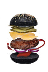 Wall Mural - Delicious hamburger with flying ingredients over white background. Layer of burger with black cuttlefish ink buns, beef cutlet, cheese, pickles, onion and tomato sauce or ketchup isolated