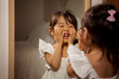 © Cavan for Adobe - Smiling little girl looking in mirror at home
