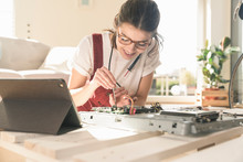 Young Woman Working On Computer Equipment At Home Next To Tablet
