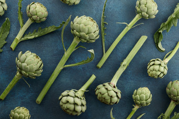 Wall Mural - Fresh green artichoke with stem and leaves on aquamarine background, top view