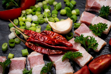 Uncured Apple Smoked Bacon, Green Onion Scallions and dried Red Chile De Arbol arranged on black natural stone background. Mexican chili pepper.