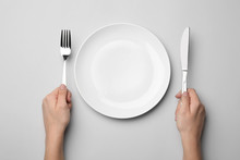 Woman With Fork, Knife And Empty Plate On Grey Background, Top View