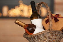 Wicker Basket With Bottles Of Wine And Gift Box Against Blurred Background, Closeup