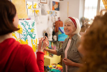 Cheerful Retired Woman Teaching Her Students To Paint