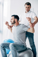 Wall Mural - chiropractor stretching arms of patient on fitness ball in hospital