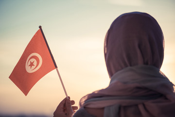 Wall Mural - Muslim woman in scarf with Tunisia flag of at sunset.Concept