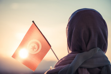 Wall Mural - Muslim woman in scarf with Tunisia flag of at sunset.Concept