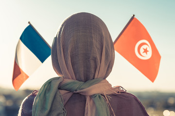 Wall Mural - Muslim woman in scarf with Tunisia and French flags of at sunset.Concept