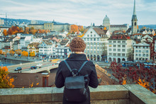 Young Blonde Tourist Girl In Warm Hat And Coat With Backpack Walking At Cold Autumn In Europe City Enjoying Her Travel In Zurich Switzerland