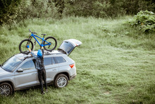 Professional cyclist taking bicycle from the car roof trunk while standing on the green meadow in the mountains. View from above