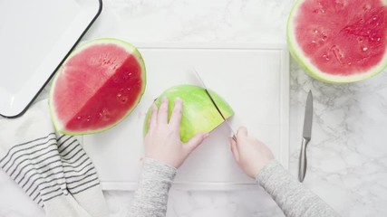 Wall Mural - Flat lay. Slicing red watermelon into small pieces on a white cutting board.