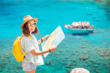 Wall Mural - Cheerful girl with a map exploring interesting places to travel by ferry or rented boat or yacht in the azure Gulf of the Mediterranean sea