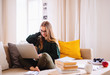 © Halfpoint - A young female student sitting on sofa, using laptop when studying.