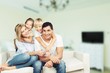 © BillionPhotos.com - Beautiful smiling family sitting at sofa at home