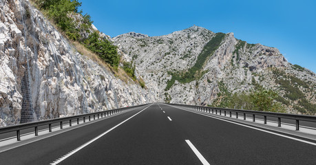 Mountain highway with blue sky and rocky mountains on a background