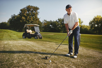 senior man teeing up his shot on a golf course