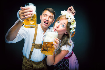  Mann und Frau stoßen mit Maß bier an und lachen auf dem Oktoberfest 