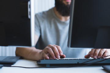 Computer programming. Cropped shot of bearded software developer using two monitors for work at office.