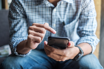 Young casual Businessman holding and using smartphone for sms messages, hipster man typing touchscreen cell phone in the cafe. business, lifestyle, technology and Social media network concept