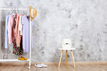 Canvas Print - Women's hip clothing store interior concept. Row of different colorful female clothes hanging on rack in hipster fashion show room in shopping mall. Grunged concrete wall background. Copy space.