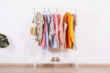 Women's Hip Clothing Store Interior Concept. Row Of Different Colorful Female Clothes Hanging On Rack In Hipster Fashion Show Room In Shopping Mall. White Wall Background. Copy Space.