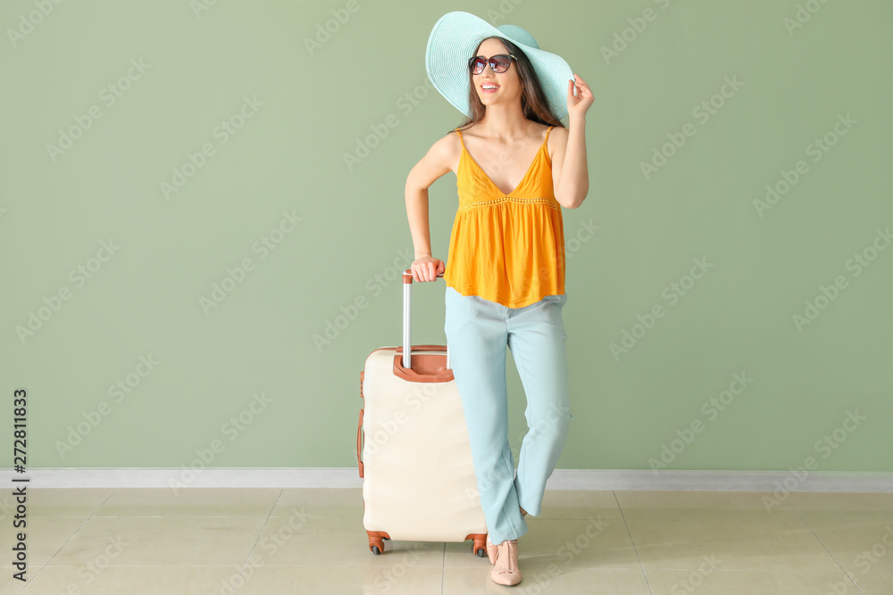 Happy young woman with suitcase near color wall