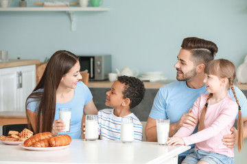 Wall Mural - Young family drinking tasty milk in kitchen at home