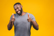 © denis_vermenko - Portrait of cheerful, positive, handsome man with black skin, beaming smile in casual showing thumb up with finger to the camera isolated on yellow background.