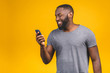 © denis_vermenko - Portrait of handsome excited cheerful joyful delightful curious guy wearing casual sending and getting messages to his lover isolated against yellow background. Using phone.