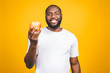 © denis_vermenko - Healthy african american man holding an apple isolated against yellow background.