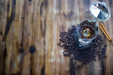 Wall Mural - The old  Italian coffee maker,mocha pot placed on wooden table there are roasted coffee beans and cinamon around with warm light in the morning tabletop view