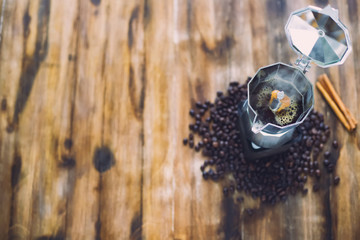 Wall Mural - The old  Italian coffee maker,mocha pot placed on wooden table there are roasted coffee beans and cinamon around with warm light in the morning tabletop view