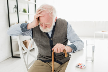 Canvas Print - Depressed senior man with walking stick, sitting at home