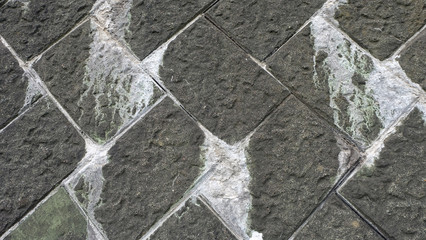 Gray tiles arranged at an angle, with white dirty deposits or stains.