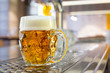 Freshly poured draft lager beer in a dimpled glass mug on stainless steel counter in a modern pub. Space for text.