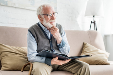 Wall Mural - Happy grey haired man holding photo album, looking away